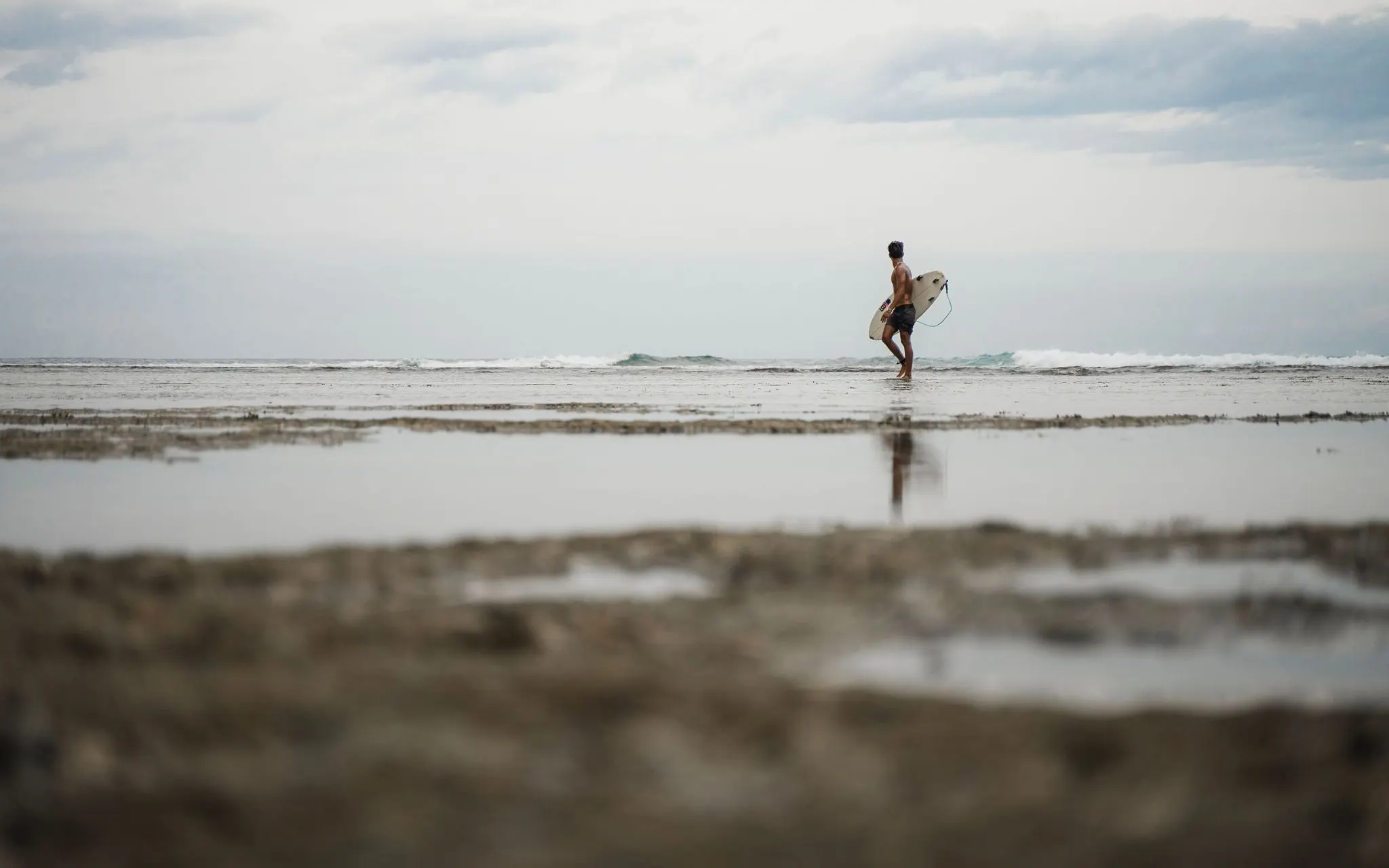 Photo: Sesinando (Pexels License) A surfer strolls along a calm, tropical beach in the Philippines