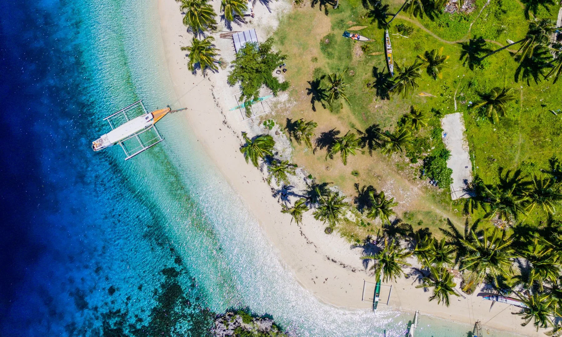Photo: Ariel Raz (Pexels License) Aerial view of a tropical beach with a boat and palm trees in Caraga, Philippines