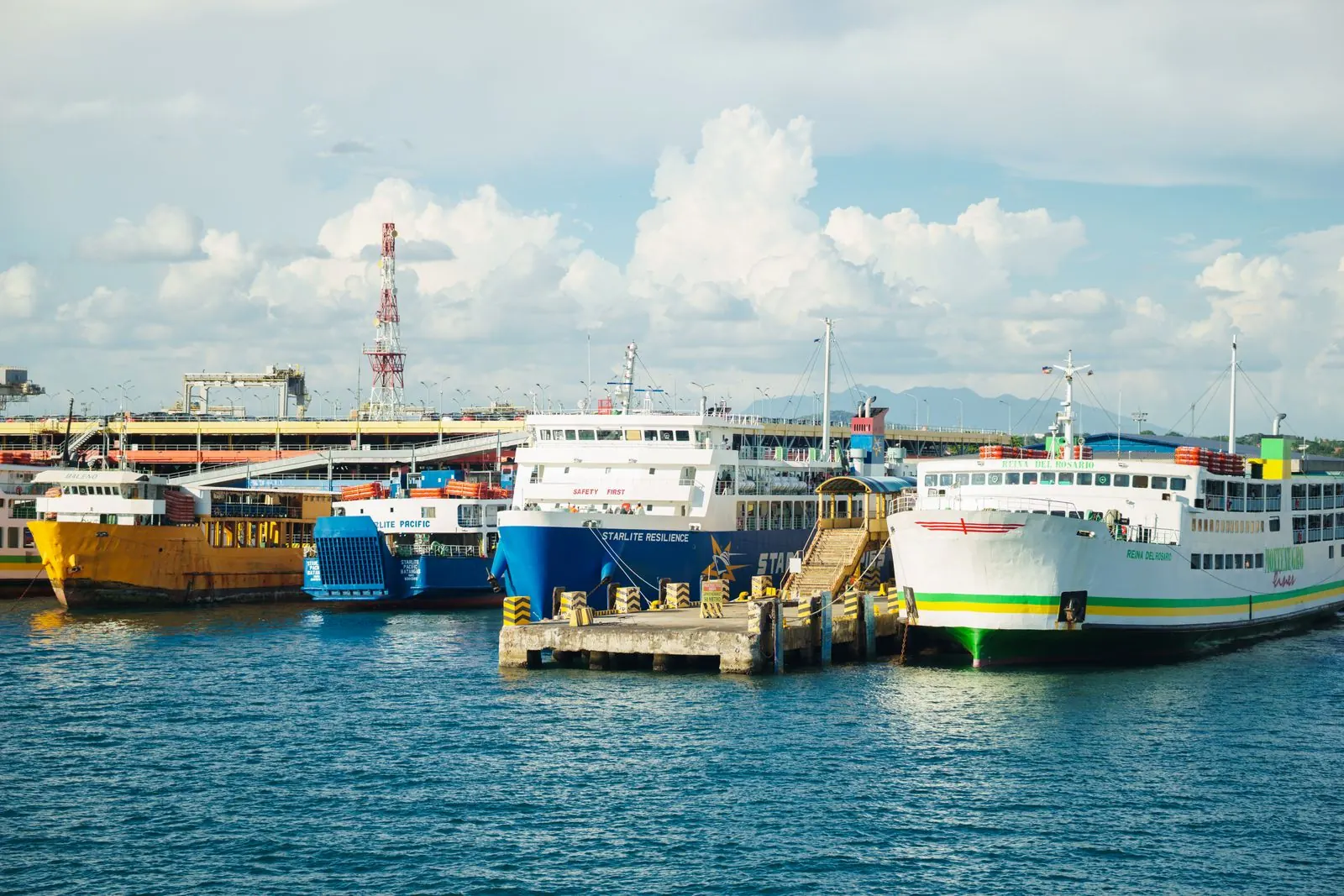Passenger ferries moored alongside a port quay under a bright blue sky