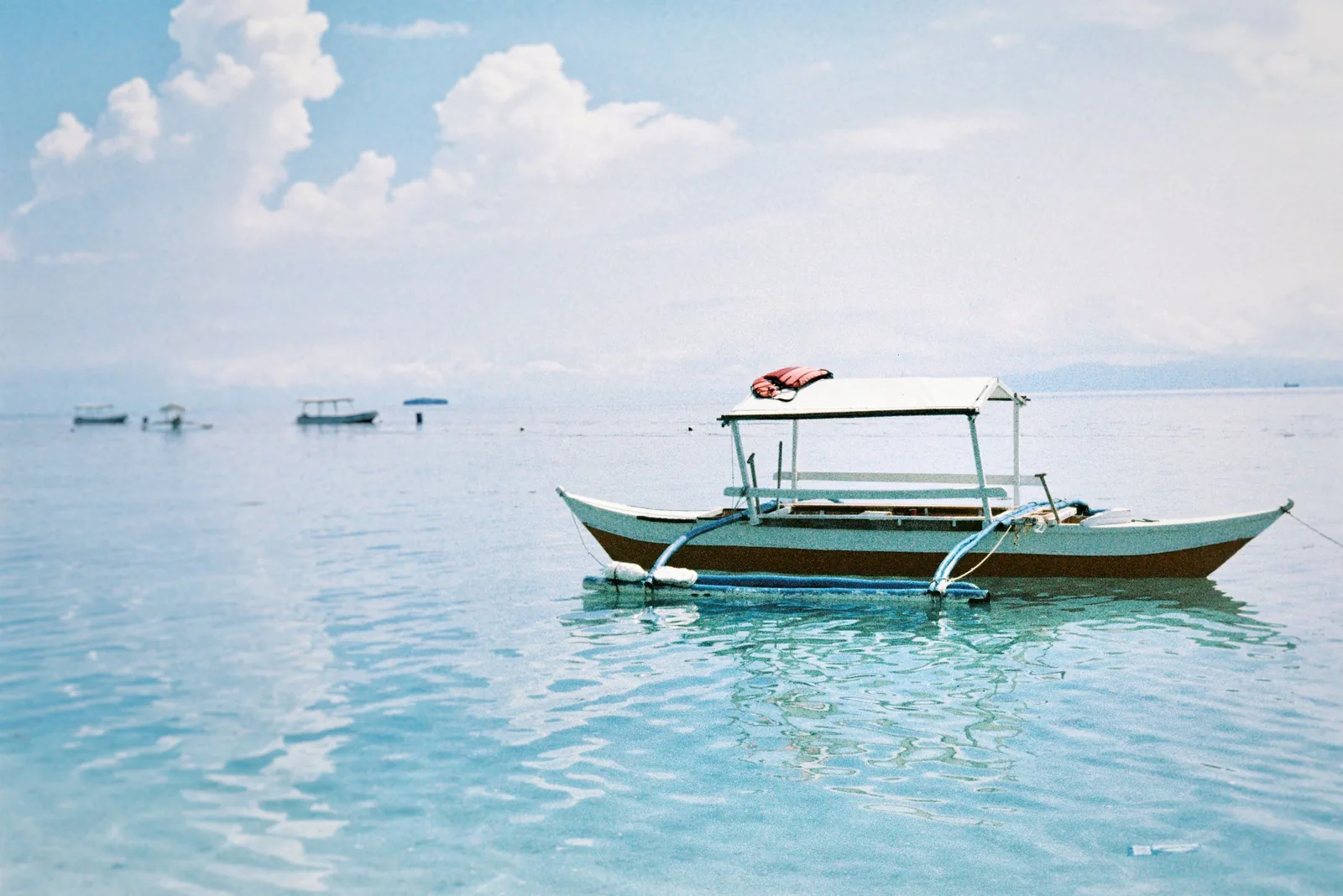 A traditional Filipino bangka outrigger boat on clear blue water
