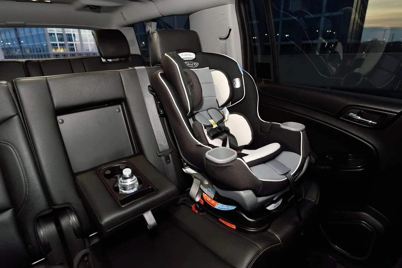 A child safety seat secured on the rear bench of a vehicle interior