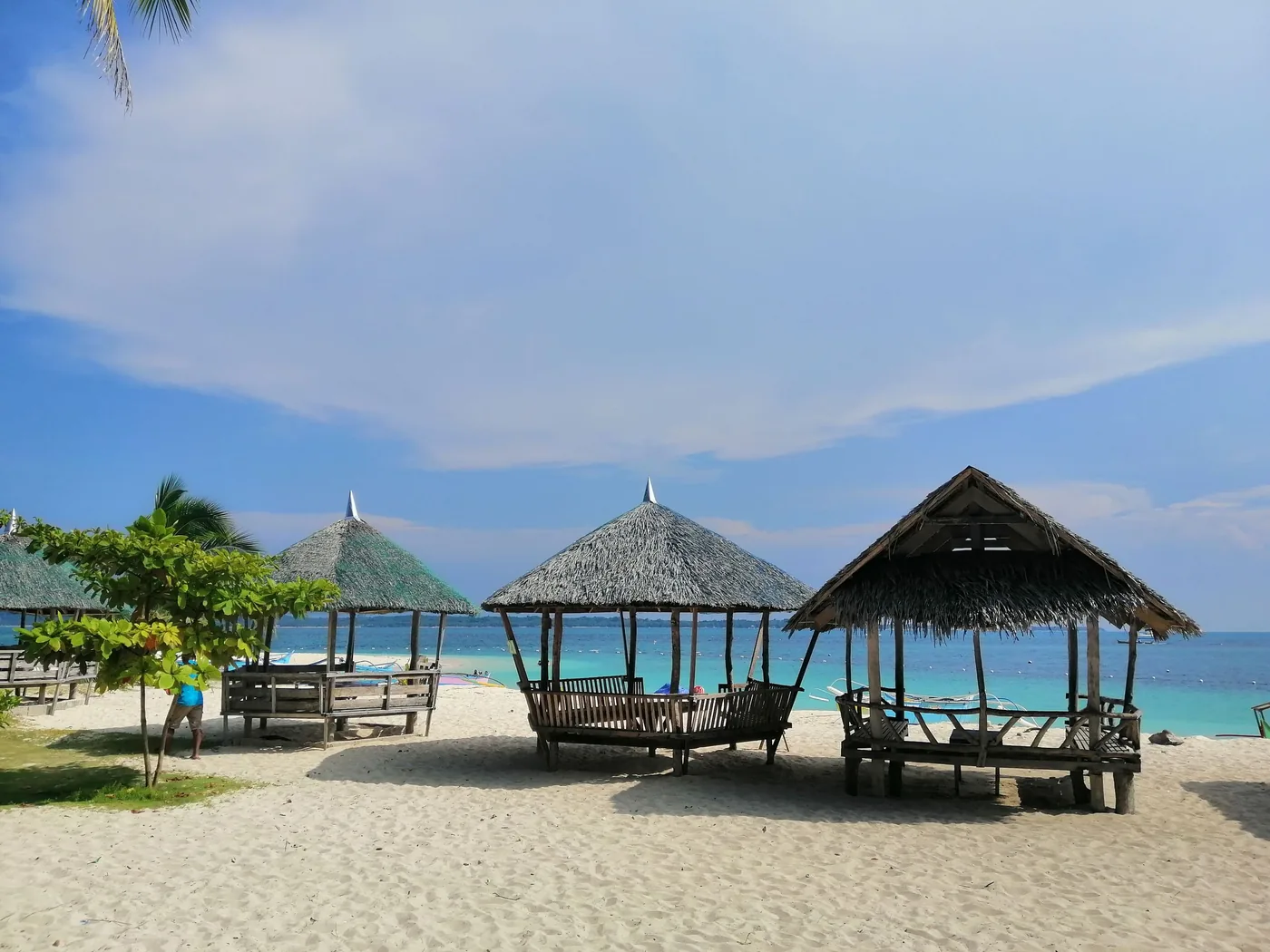 Timber beach huts under palm trees on the sand at a shorefront in Caraga, Philippines
